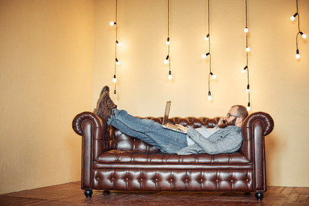 lifestyle successful freelancer man with beard achieves new goal with laptop in loft interiorの写真素材