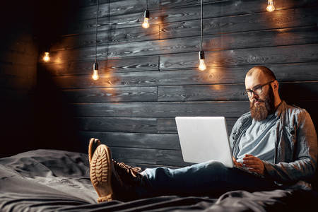 lifestyle successful freelancer man with beard achieves new goal with laptop in loft interiorの写真素材