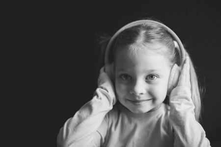 little girl in headphones listening to music, black and white portrait of a Caucasian childの写真素材