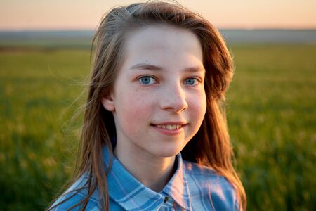 portrait of a teenage girl in a field at sunsetの写真素材