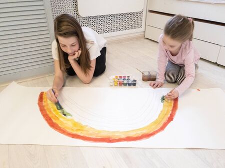 two sisters paint a rainbow with watercolors as a symbol of hope while fighting the coronavirus, stay at home-social media campaign.の写真素材