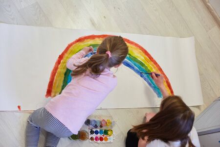 two sisters paint a rainbow with watercolors as a symbol of hope while fighting the coronavirus, stay at home-social media campaignの写真素材