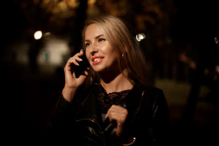 beautiful blonde woman talking on the phone in the evening in the Park, communication and communicationの写真素材