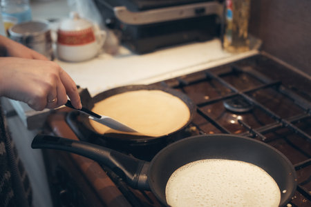 russian woman bakes pancakes in a frying panの写真素材
