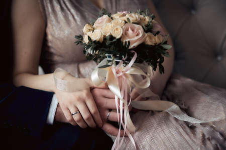 hands of the bride and groom with wedding rings and bouquet close upの写真素材