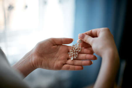 A beautiful bride in a long dress at the hotel and waiting for the groom. jewels of the brideの写真素材
