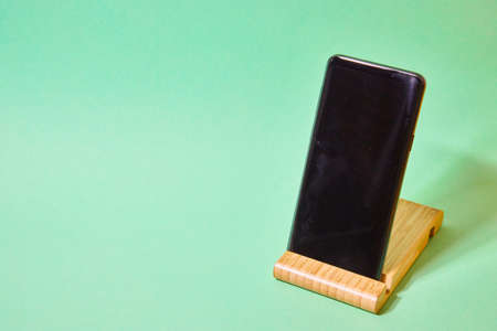 smartphone on a wooden stand on a green backgroundの写真素材