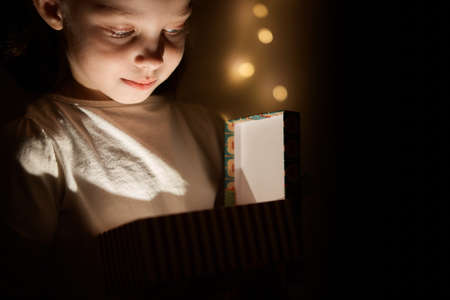 a little girl opens a glowing gift boxの写真素材