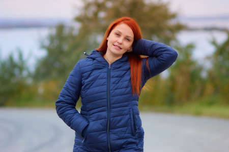 portrait of a life style woman with red hair in autumn against a background of colorful foliageの写真素材