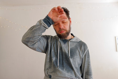 bearded tired man wipes sweat after hard workの写真素材