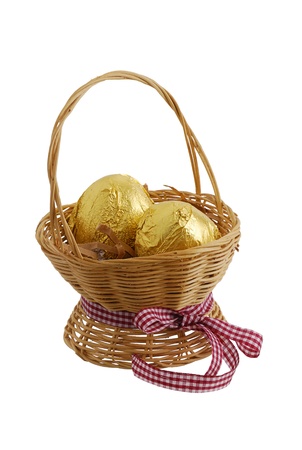 Two eggs wrapped in golden foil in straw interwoven basket with ribbon isolated on white backgroundの写真素材