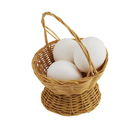 Top view of three white eggs in straw interwoven basket isolated on white backgroundの写真素材
