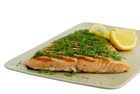 Salmon fish fillet grilled with green vegetables and lemon isolated on white backgroundの写真素材