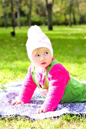 Small beautiful girl on green herb by autumnの写真素材