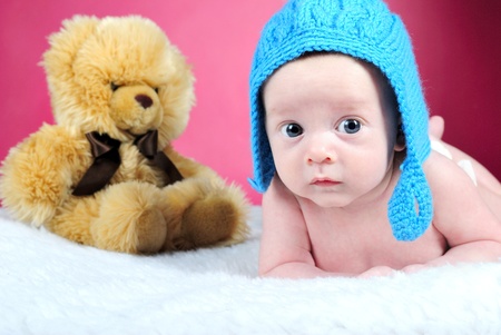The little boy with the big eyes on a pink background in a dark blue cap with a bear の写真素材
