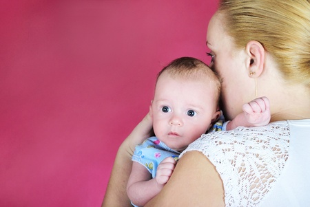 The little boy with the big eyes at mum on hands on a pink background の写真素材