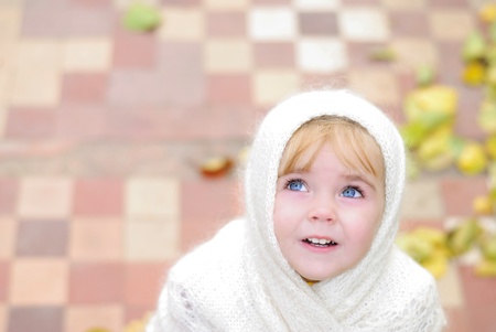 Portrait of the small beautiful girl in a white scarf Looking upwardsの写真素材
