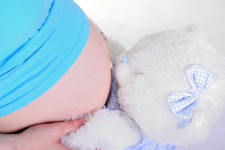 Stomach of the pregnant girl in embraces of a teddy bear の写真素材