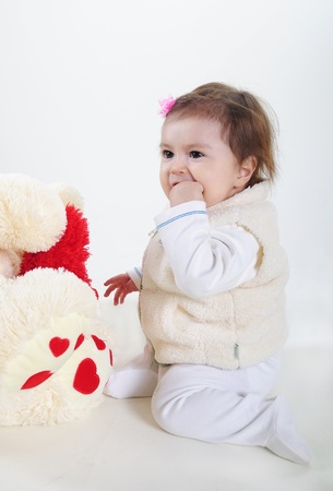 The small beautiful girl lies on a white background with toysの写真素材