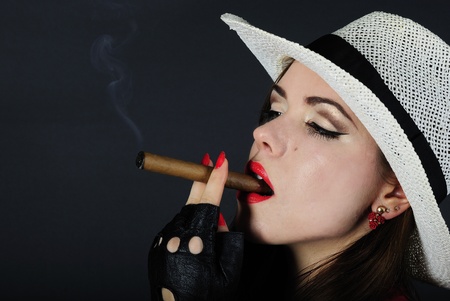 making look younger beautiful girl with red pomade with cigar in black hatの写真素材