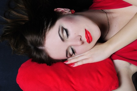making look younger beautiful bright girl sleeps on red pillowの写真素材