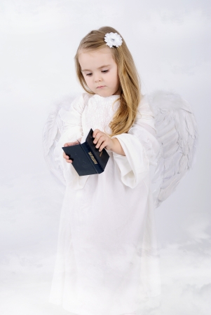 A beautiful little girl angel with a bookの写真素材