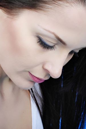 Beautiful girl brunette with long hair on turn blue background looks downwards
の写真素材
