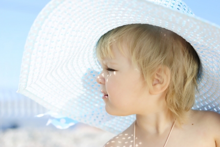 a little girl in large hat on the shore of the sea in the summerの写真素材