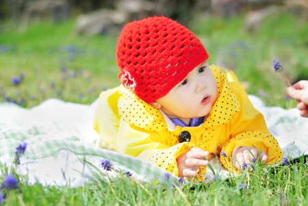 little girl on a green meadow in a bright yellow jacketの写真素材