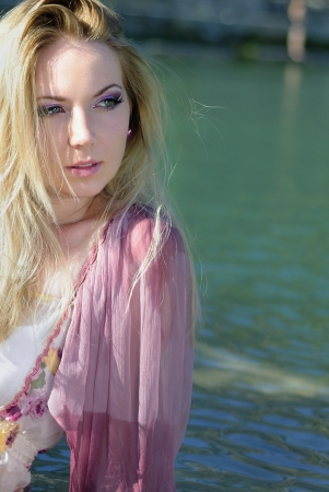 Beautiful blonde in water with flowerの写真素材