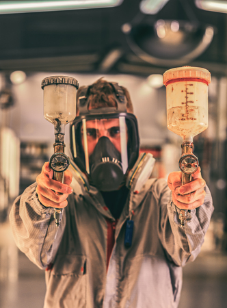 mechanic in overalls, with a spray gun in his hands. Paint shop. Automobile productionの写真素材