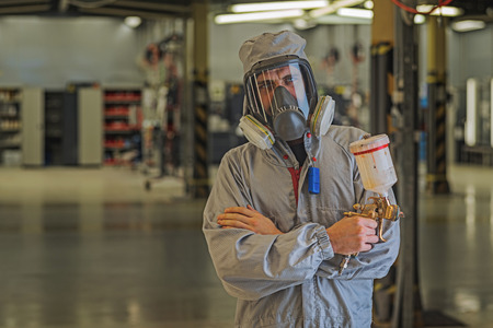 mechanic in overalls, with a spray gun in his hands. Paint shop. Automobile production
