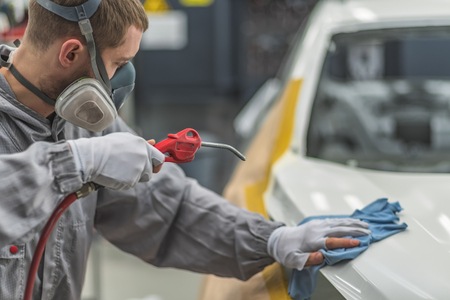 Employee car body painting shop prepares the surface for painting, removes dustの写真素材