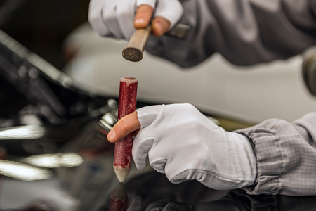 An employee of the car body painting shop eliminates a small metal defect with a special hand toolの写真素材