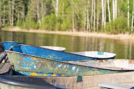 old rowing boats moored on the shore against the green forest.の写真素材