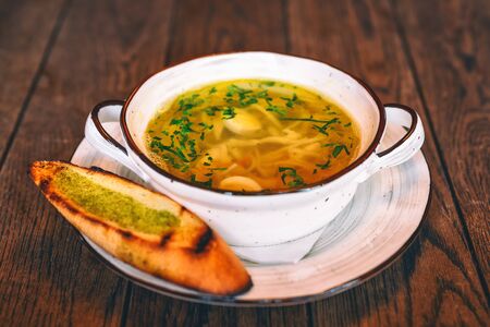 Chicken soup in a plate with toasted slices of bread on the sideの写真素材