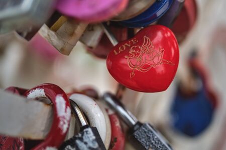 The red castle in the form of a heart hangs on an old metal fenceの写真素材