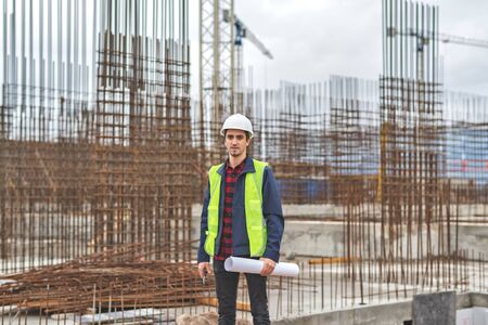 civil engineer in a white helmet on the background of houses under construction.