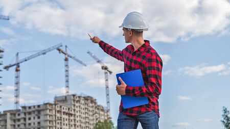 civil engineer in a white helmet on the background of houses under construction.の写真素材