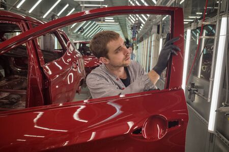 Employee car body painting shop checks the quality of the painted surfaceの写真素材