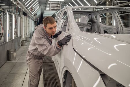 Employee car body painting shop checks the quality of the painted surfaceの写真素材