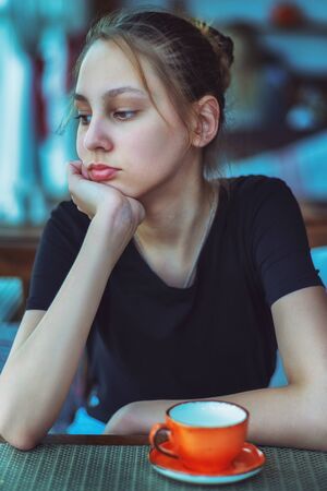 portrait of a girl sitting in a cafe with a Cup on the table.の写真素材