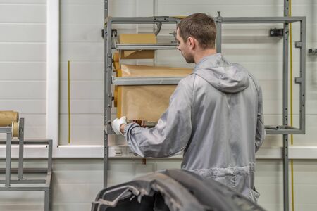 An employee of the paint shop of the automobile plant is preparing bumpers for painting. Industrial...