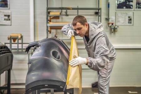 An employee of the paint shop of the automobile plant is preparing bumpers for painting. Industrial interiors.の写真素材