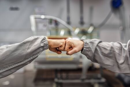 Friendly handshake of two employees of the paint shop. Industrial interiors.の写真素材
