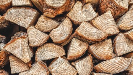 The pile of firewood close-up. Pile of dry wood, visible texture and cracks in the wood. An outside...