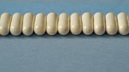 White capsules are isolated on a blue background. The concept of medicine. Close-up, selective focus