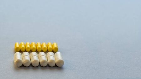 Yellow and white capsules are isolated on a blue background. Top view with space for copying. Concept of medicine. Close-up, selective focusの写真素材