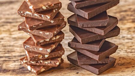 pieces of different milk chocolate are neatly arranged on a wooden stand in columns