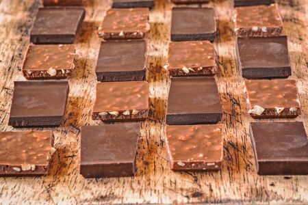 pieces of different milk chocolate are neatly arranged on a wooden stand in a staggered order